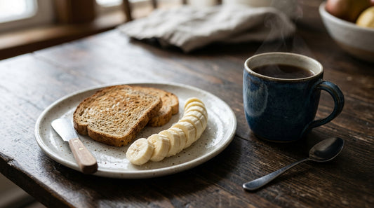 Desayuno ligero con plátano, pan tostado y bebida caliente sobre mesa de madera oscura antes de entrenar